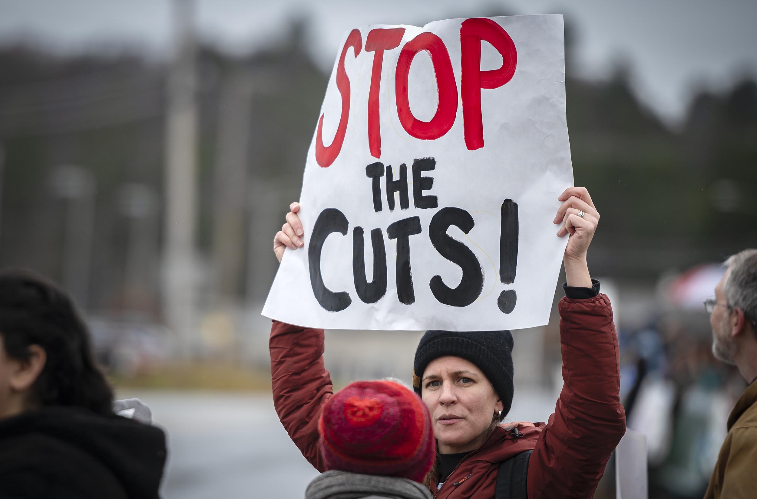 A person holds up a reading sign "Stop the Gaps" during an external protest.